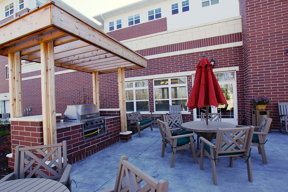 Bbq area with tables and umbrellas at Oak Hill Supportive Living Community