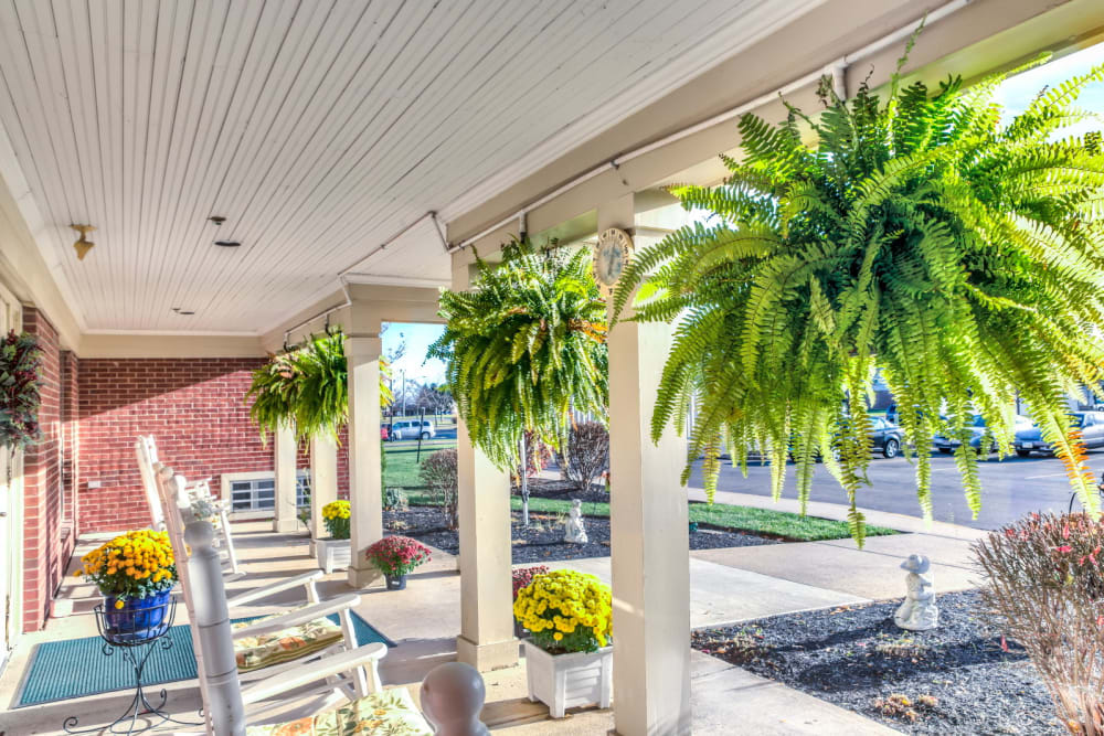 Inivting porch with ample white rocking chair seating and foliage at Carriage Court of Washington Court House in Washington Court House, Ohio