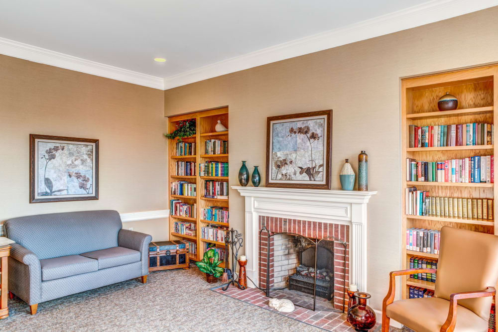 Sitting area complete with wood bookshelf and cozy fireplace at Carriage Court of Lancaster in Lancaster, Ohio