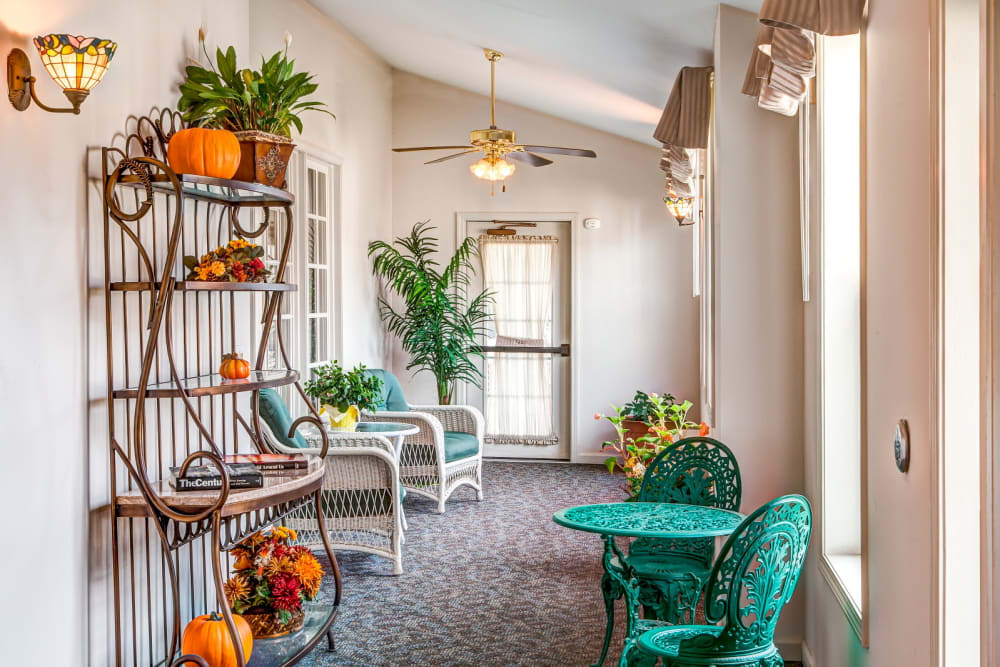 Sun room complete with elegant green seating and table at Grand Victorian of Sycamore in Sycamore, Illinois