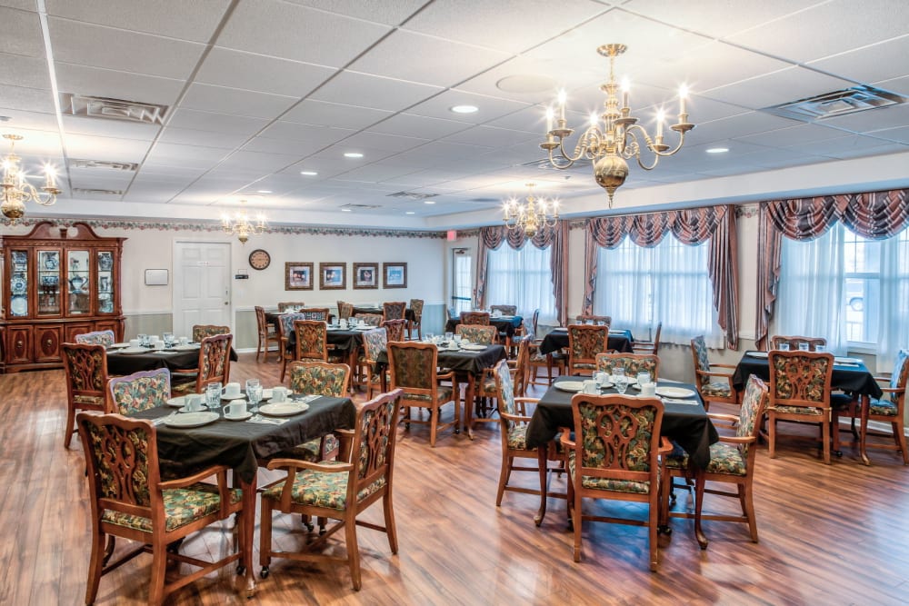Elegant dining room with chandeliers and wood accents  at Grand Victorian of Sycamore in Sycamore, Illinois