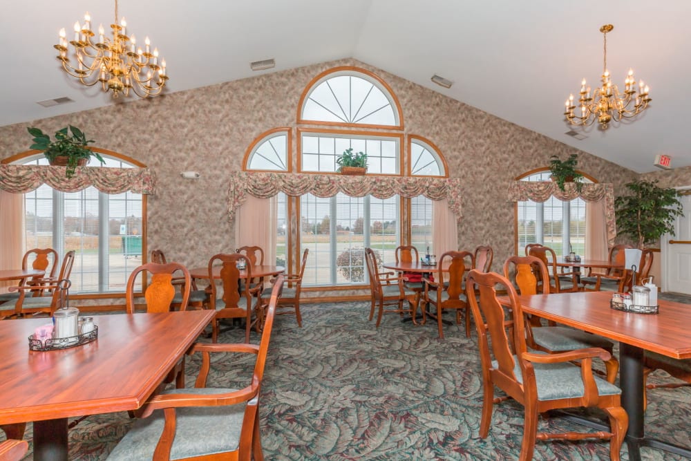 Elegant dining room with wood tables, large windows, and chandeliers at Brookstone Estates of Paris in Paris, Illinois