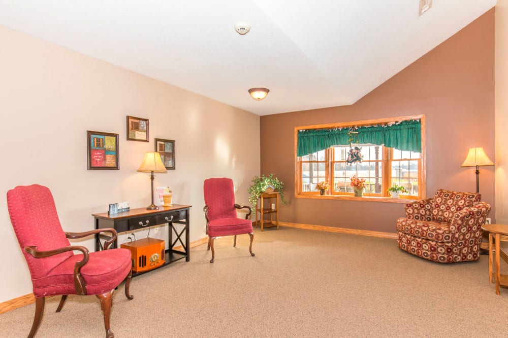Comfortable lounge with elegant red chairs and window at Emerald Glen of Olney in Olney, Illinois