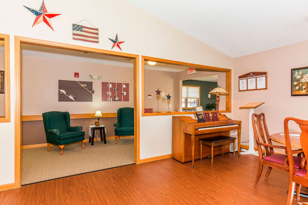 Sitting room complete with green chairs, table, and piano at Emerald Glen of Olney in Olney, Illinois