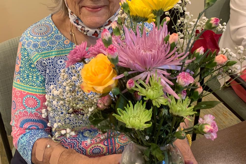 Female resident smiling and holding flowers enjoying life at Azpira at Windermere | Pathway to Living