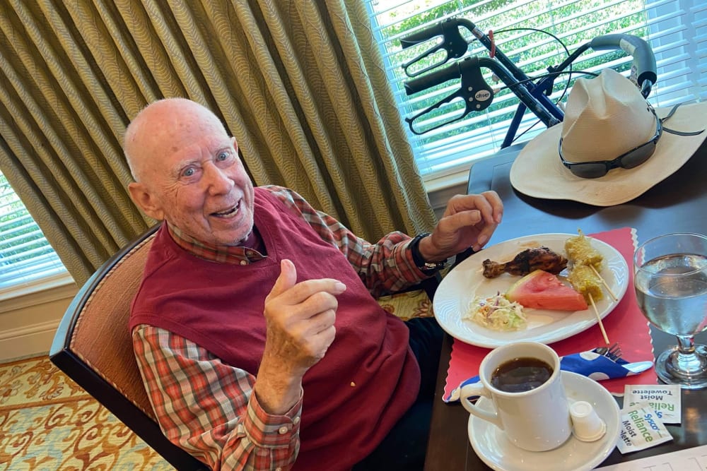 Male resident smiling and giving thumbs up while eating delicious food at Azpira at Windermere | Pathway to Living
