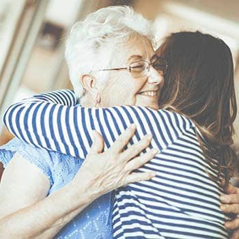 Resident and family member hugging at Grand Victorian of Sycamore in Sycamore, Illinois. 