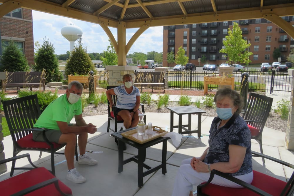 Group of residents sitting outside under a gazebo on a sunny day at Aspired Living of La Grange in La Grange, Illinois