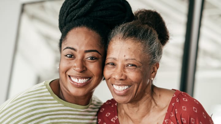 Mother-in-red-shirt-and-daughter-in-green-shirt-embrace-and-smile