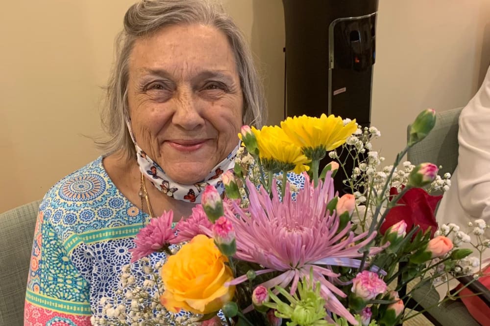 Woman resident smiling and holding flowers at Azpira at Windermere | Pathway to Living