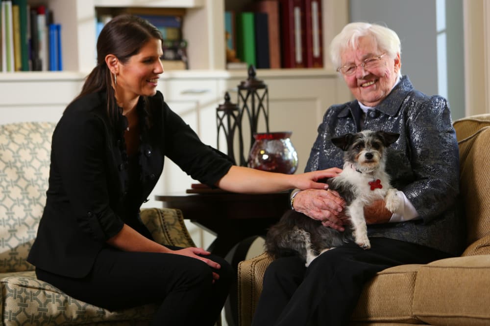 Cheerful resident with her dog and a friendly staff member at Brookstone Estates of Robinson in Robinson, Illinois