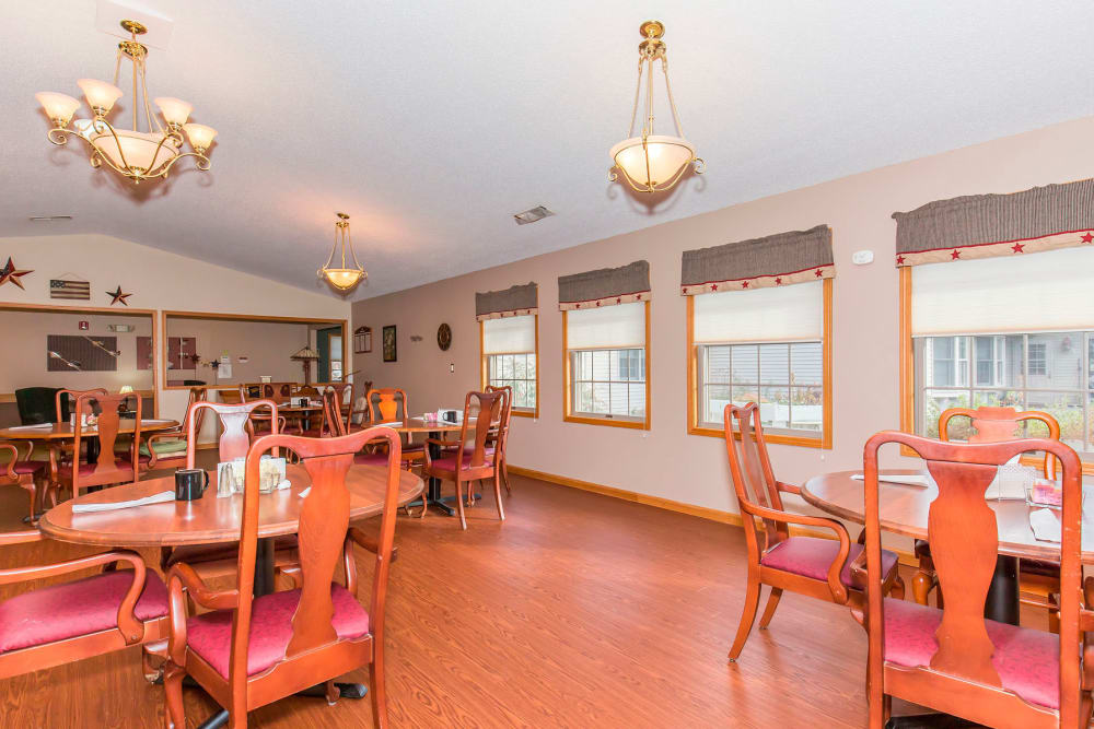 Elegant dining room with chandeliers and hardwood floor at Emerald Glen of Olney in Olney, Illinois