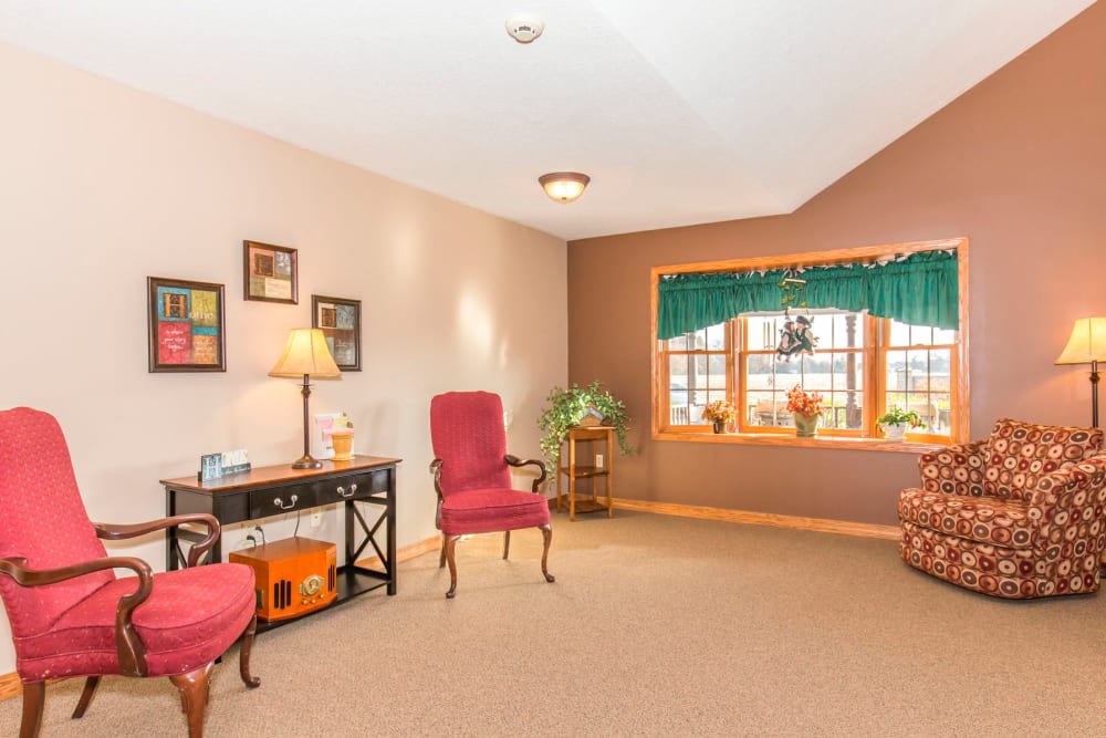 Airy and well lit sitting room complete with window and red chairs at Emerald Glen of Olney in Olney, Illinois