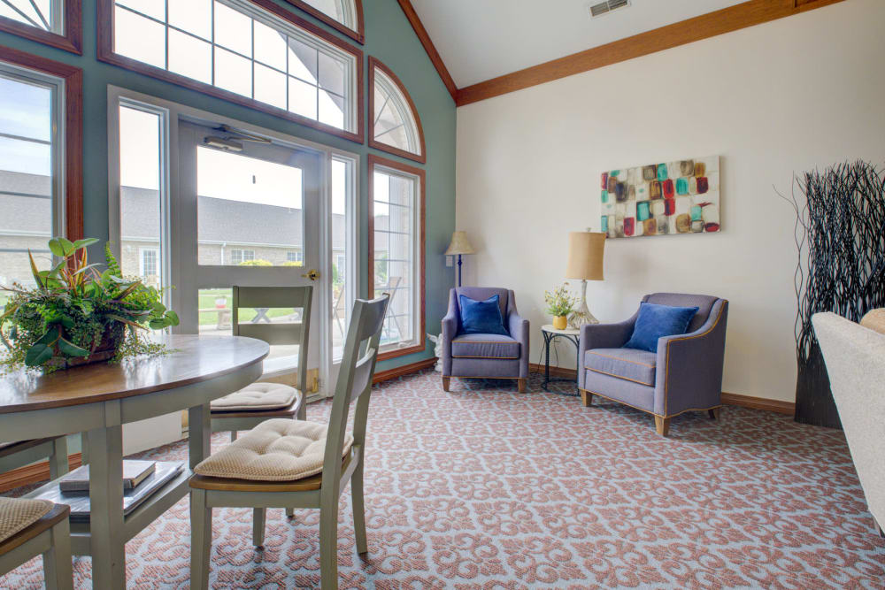 Brightly lit room with foliage, artwork, and armchairs at Brookstone Estates of Vandalia in Vandalia, Illinois