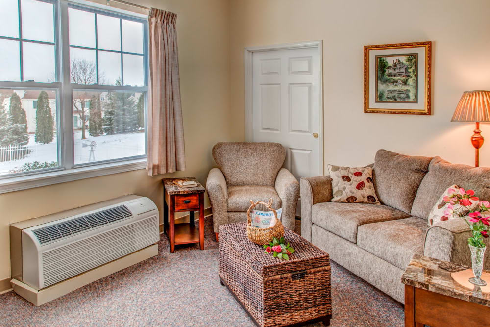 Comfy apartment in upscale senior living facility complete with armchairs and rustic snowy view at Grand Victorian of Rockford in Rockford, Illinois