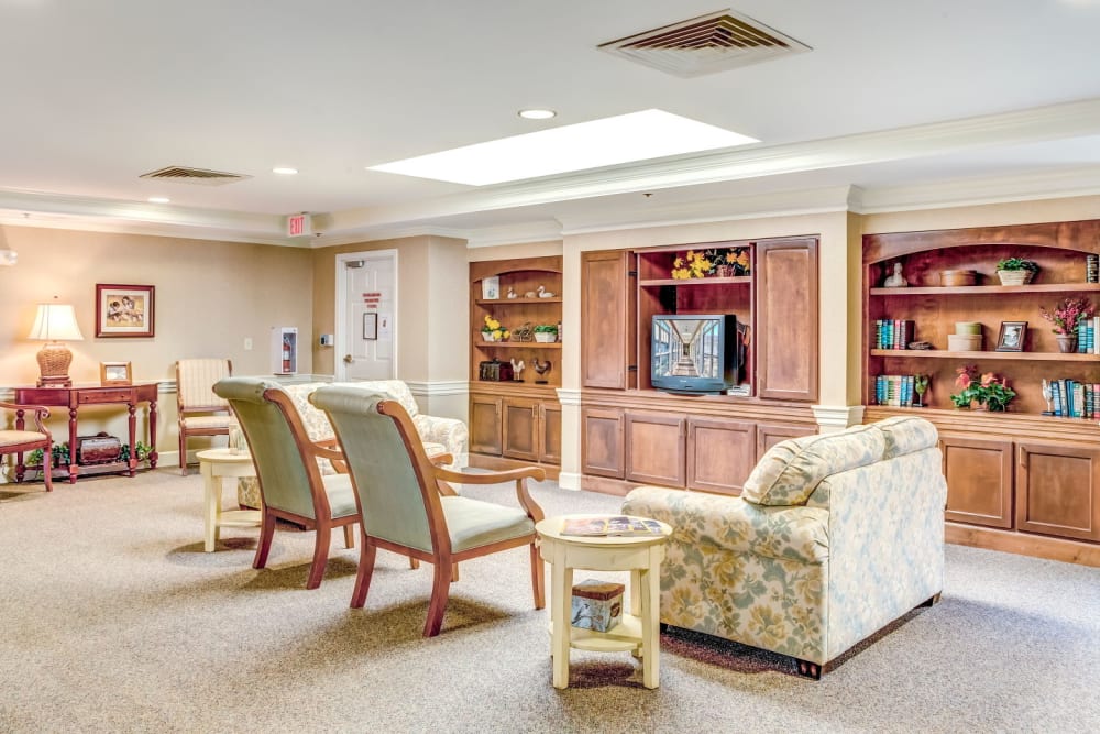 Community living room with television seat, wood accents, and bookcase at Carriage Court of Washington Court House in Washington Court House, Ohio