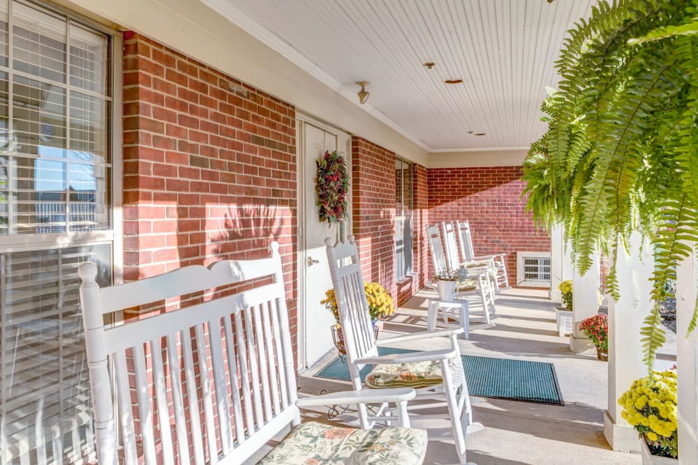 Porch seating with white rocking chairs and foliage at Carriage Court of Washington Court House in Washington Court House, Ohio