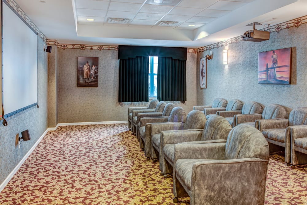  Community theater with 12 soft chairs arranged in 2 rows in front of a projection screen at Grand Victorian of Rockford in Rockford, Illinois