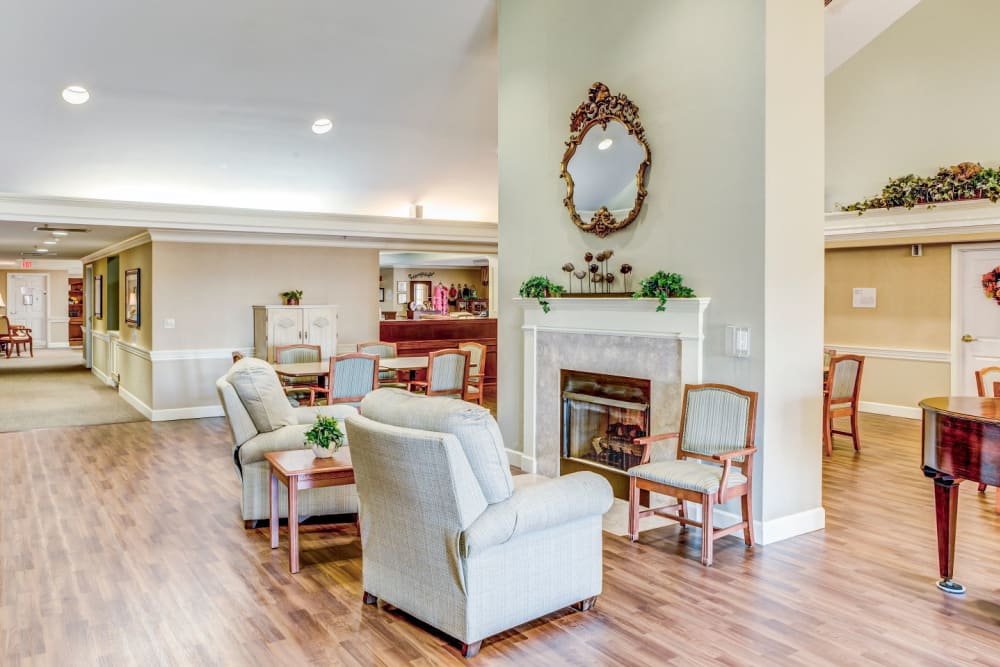 Elegant white walled living room area with tract lighting, armchairs, and fireplace at Carriage Court of Washington Court House in Washington Court House, Ohio