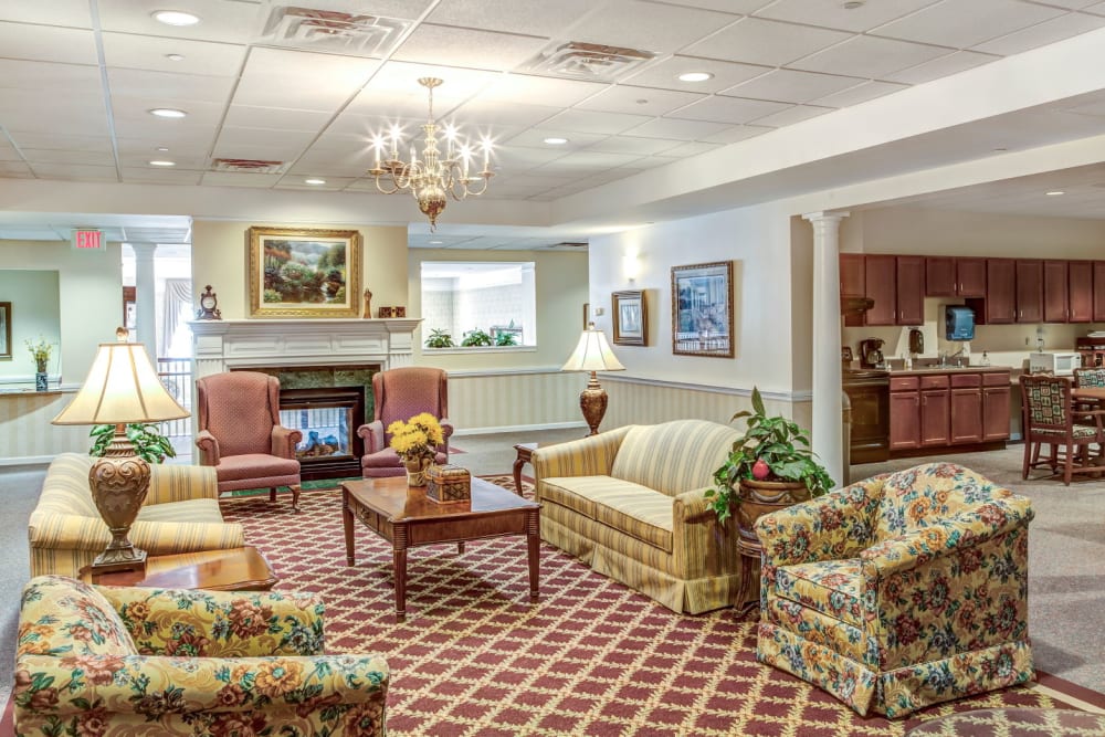Ornate communal sitting area with armchairs, chandeliers,  tract light, and fireplace at Grand Victorian of Rockford in Rockford, Illinois