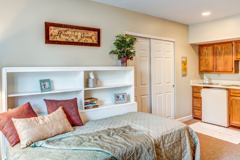 Brightly lit apartment with bed and kitchen with wood accents at Carriage Court of Lancaster in Lancaster, Ohio