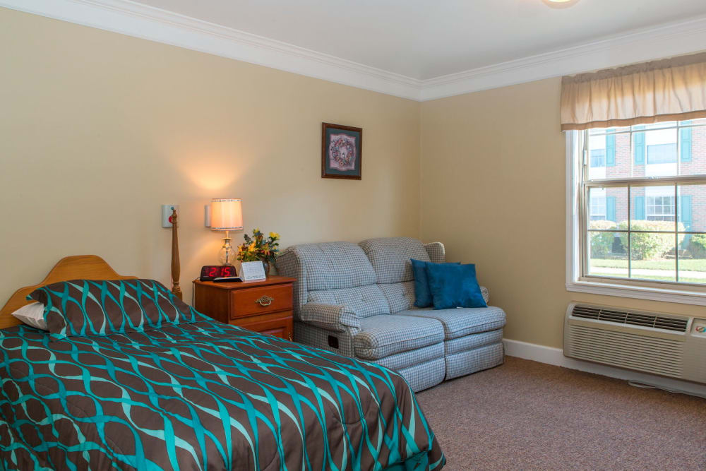 Bedroom complete with comfy sofa and window lighting in upscale senior living facility at Carriage Court of Washington Court House in Washington Court House, Ohio