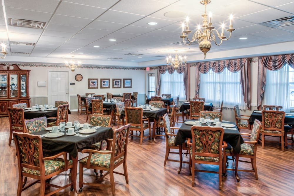Ornate communal dining area with wood accents and chandeliers at Grand Victorian of Sycamore in Sycamore, Illinois