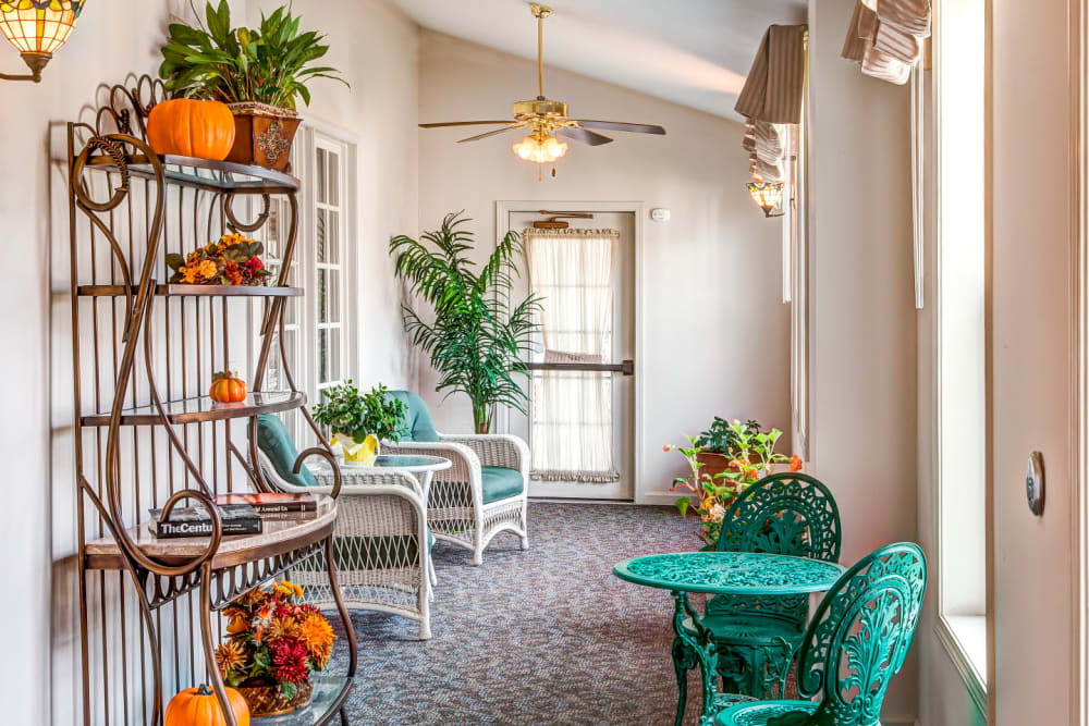 Charming sunroom with elegant green patio chairs and table at Grand Victorian of Sycamore in Sycamore, Illinois