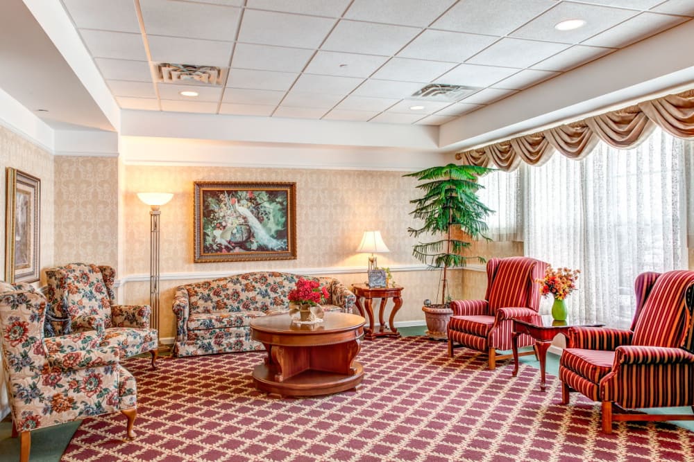 Cheerful red communal living room area complete with paintings and foliage at Grand Victorian of Rockford in Rockford, Illinois