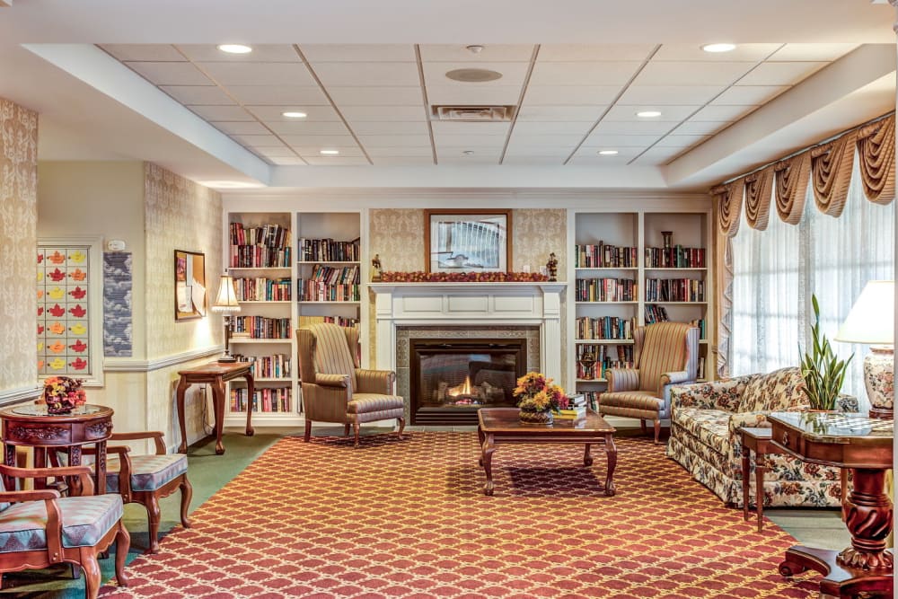 Comfortable seating area with amble bookcases and inviting fireplace at Grand Victorian of Sycamore in Sycamore, Illinois