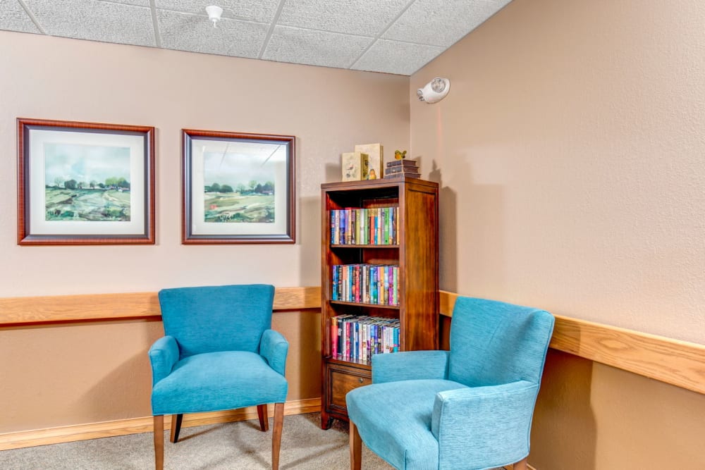 Well lit library area with vibrant blue chairs at Brookstone Estates of Olney in Olney, Illinois
