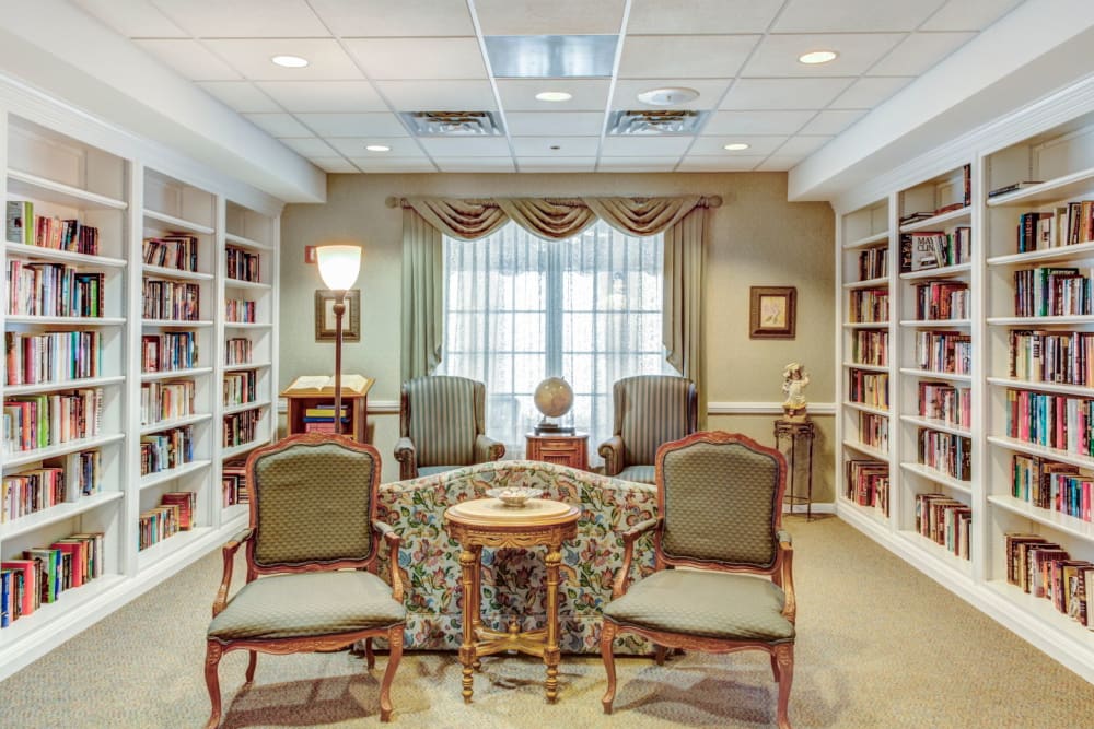 Communal reading area with wood bookshelves and bright lighting at Grand Victorian of Rockford in Rockford, Illinois