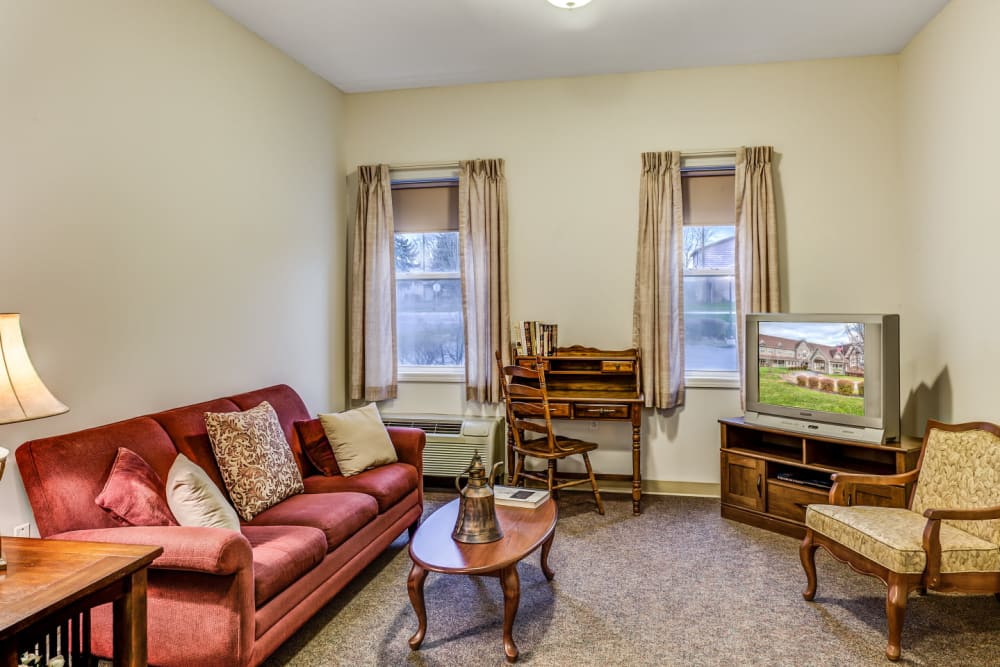 Living room of apartment unit with comforable seating and television set at Grand Victorian of Sycamore in Sycamore, Illinois