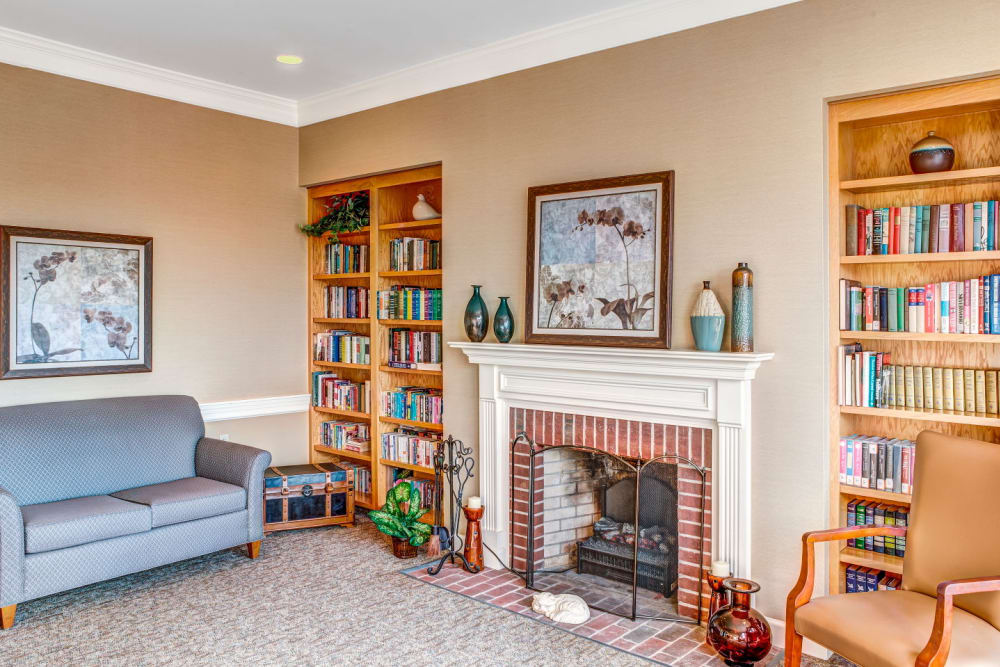 Reading room with copious books in elegant wood bookcase and fireplace at Carriage Court of Lancaster in Lancaster, Ohio